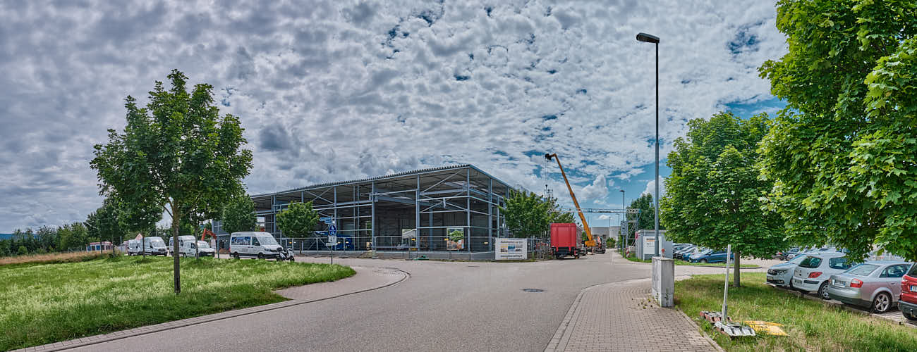 Gewerbegebäude mit Bagger und Autos auf Parkplatz